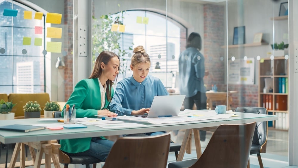 Cultivating-Company-Culture-Through-Technology-Enabled-Onboarding-two-colleagues-collaborating-modern-office=-laptop